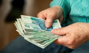 Dłonie liczą banknoty. Czy to dodatek do emerytury za warunki szkodliwe?