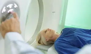 Pacjentka leży na stole do badania, a technik przygotowuje badanie tk.