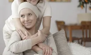 Dwie kobiety przytulają się. Jedna z nich, w chustce na głowie, uśmiecha się. To obraz wsparcia w trudnych chwilach, gdzie leczenie paliatywne oferuje komfort i godność.