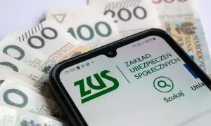 Zasiłek dla bezrobotnych a emerytura – telefon z aplikacją ZUS na tle polskich banknotów.