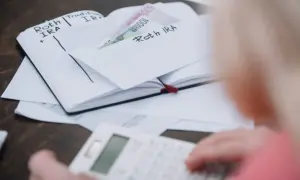 Osoba liczy pieniądze w zeszycie z wpisami "Roth IRA", zastanawiając się, czy studia liczą się do emerytury.