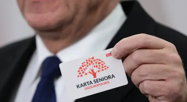 Mężczyzna prezentuje kartę seniora z czerwonym drzewem. To ogólnopolska karta uprawniająca do zniżek.