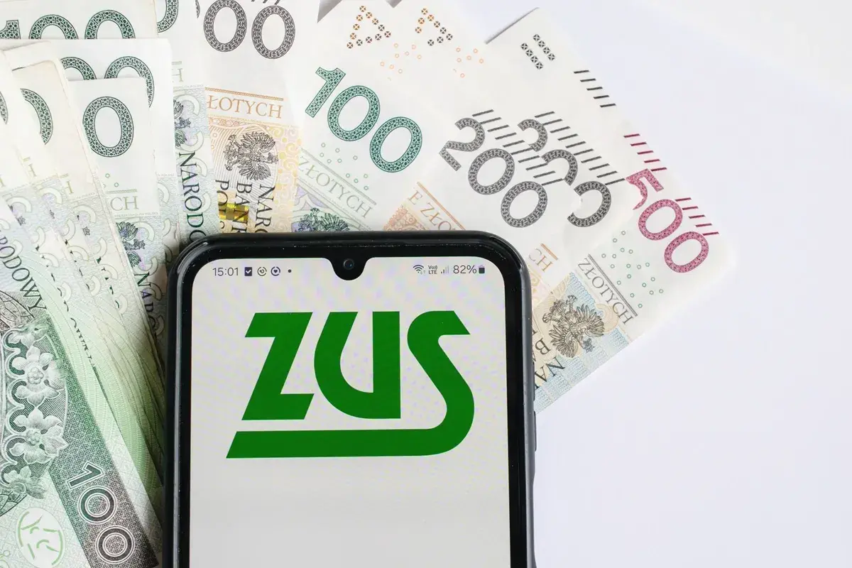 Nowe przepisy ZUS w sprawie emerytur. Na ekranie telefonu logo ZUS, w tle polskie banknoty.