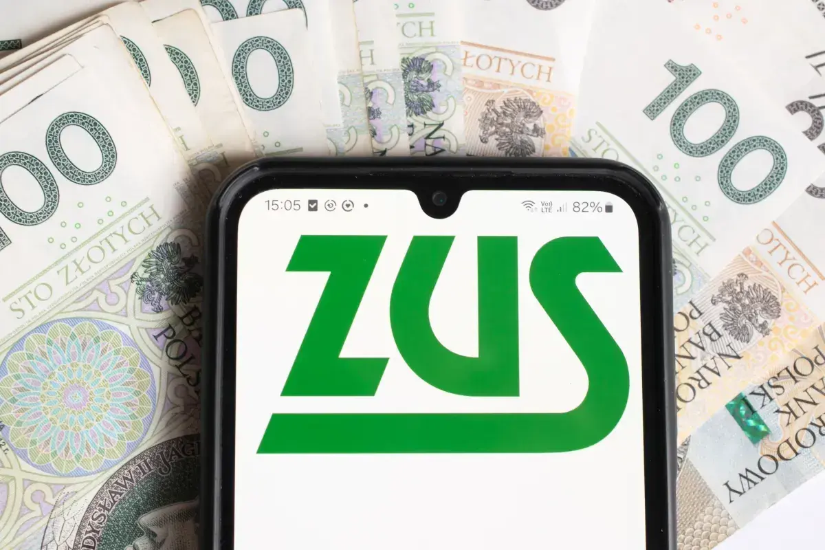 ZUS na ekranie telefonu, otoczony banknotami 100 zł. Sprawdzam, czy renta wdowia ma limit.