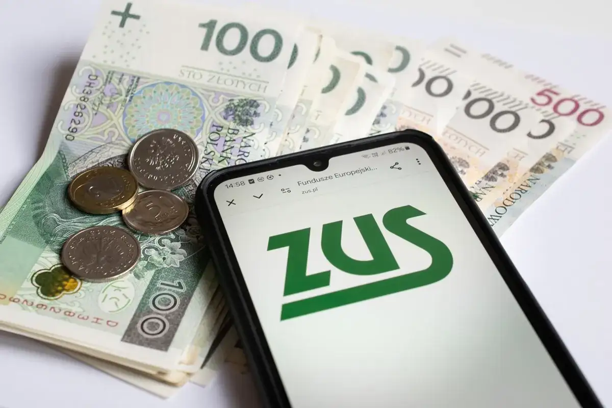Pieniądze i telefon z logo ZUS. Może to symbolizować zwrot składki zdrowotnej lub inne rozliczenia z ZUS.