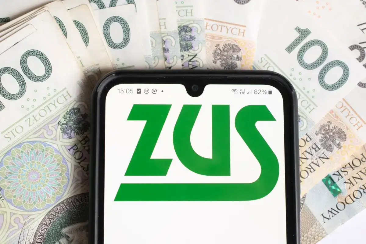 ZUS na ekranie telefonu, otoczony banknotami 100 zł. Sprawdzam, czy renta wdowia ma limit.