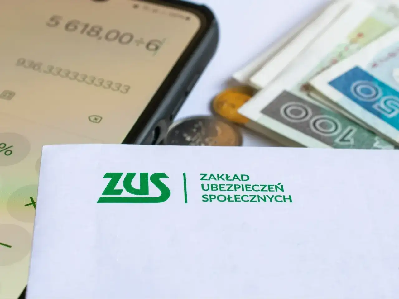 ZUS, pieniądze i kalkulator na ekranie telefonu sugerują analizę waloryzacji emerytur 2026. Tabela z prognozami jest kluczowa.
