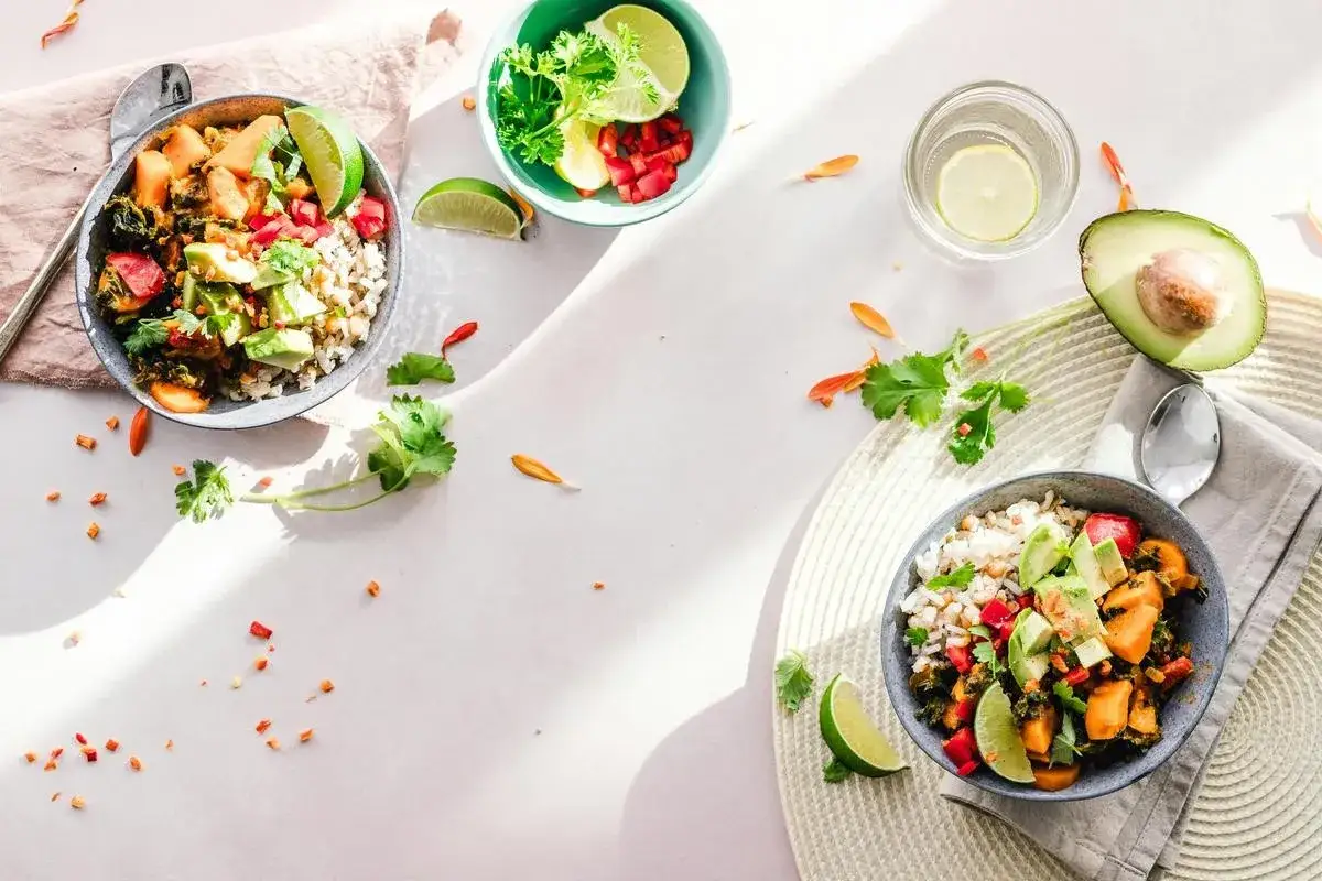 Dwa miski pełne zdrowych składników, idealne na dietę niskotłuszczową. Ryż, awokado, warzywa i limonka tworzą apetyczną kompozycję.