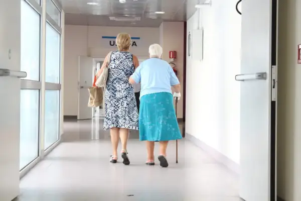 Dwie kobiety idą korytarzem szpitalnym. Jedna z nich wspiera się laską. Zastanawiają się, ile zwrotu mogą uzyskać z ulgi rehabilitacyjnej 2280.