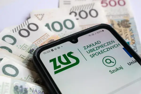 Zasiłek dla bezrobotnych a emerytura – telefon z aplikacją ZUS na tle polskich banknotów.